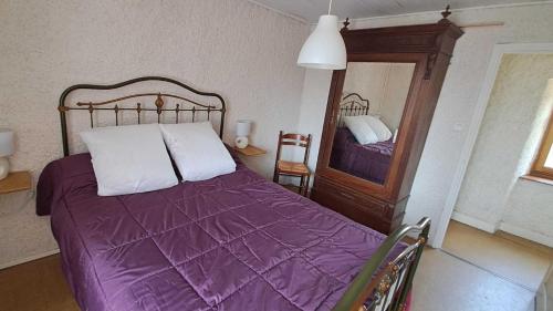 a bedroom with a purple bed and a mirror at La castagnal in Jouqueviel