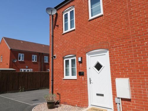 a red brick building with a white door on it at Ty Bach Twt Llanelli in Llanelli