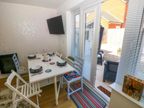 a dining room with a white table and chairs at Ty Bach Twt Llanelli in Llanelli