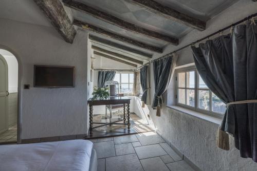 a bedroom with a bed and a table and windows at Château Le Cagnard in Cagnes-sur-Mer