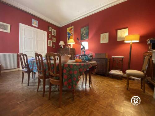 una sala da pranzo con tavolo, sedie e pareti rosse di La maison bachelet a Claira