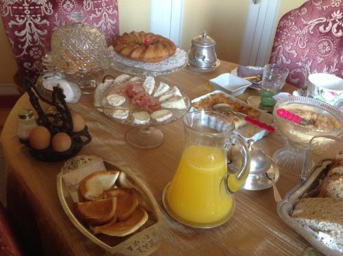 a table with breakfast foods and a jug of orange juice at La Demeure aux Hortensias in Pleurtuit