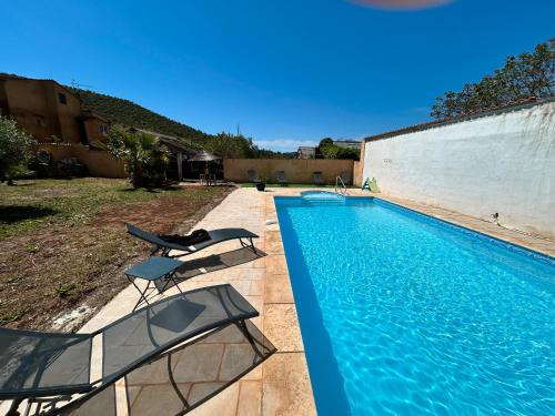 a swimming pool with two chairs next to a building at Domaine des Oliviers - Les Borrels in Hyères