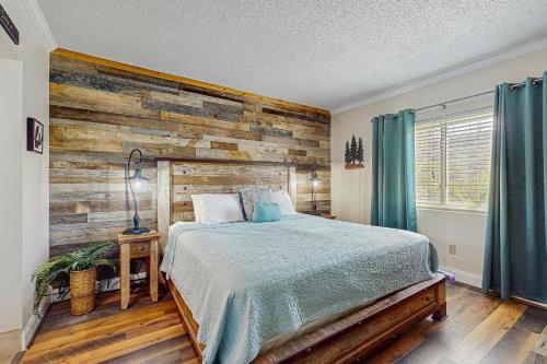 a bedroom with a bed and a wooden wall at Rivers Edge Condo 206 in Pigeon Forge
