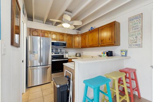 a kitchen with a refrigerator and two stools at Mallard Lakes - 142 Cardinal in Selbyville