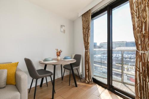a living room with a table and chairs and a large window at 1 Bedroom Apartment near City Airport in London