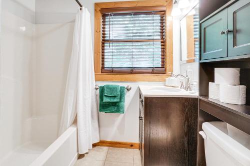 a bathroom with a white tub and a sink at 5 Mi to Helen Hideaway with Deck and Grill! in Sautee Nacoochee