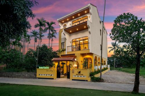 a large house with a sunset in the background at Naraco Homestay Hoi An in Cam Thanh