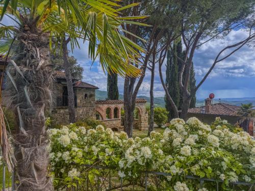 a stone house surrounded by trees and flowers at Ferienwohnung Fortuna del Lupo mit Pool und Aussicht in Subbiano