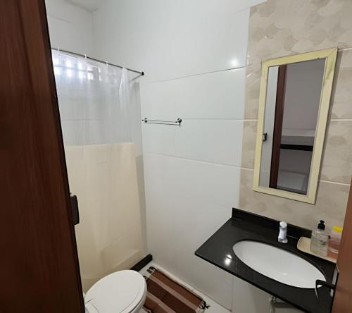 a bathroom with a toilet and a sink and a mirror at Viva sol hospedagem in Cabo Frio