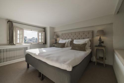 a bedroom with a large white bed with a window at Château Le Cagnard in Cagnes-sur-Mer