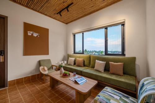 a living room with a green couch and a table at Naraco Homestay Hoi An in Cam Thanh