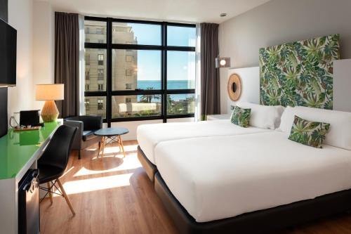 a hotel room with a white bed and a desk at Catalonia Málaga in Málaga