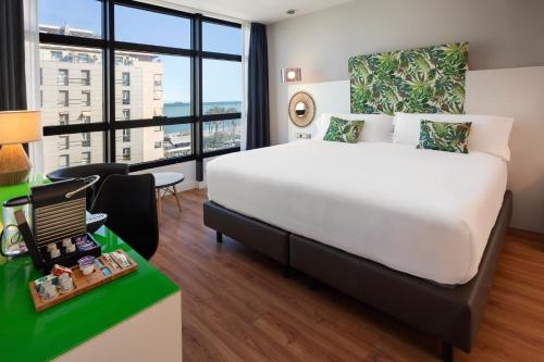 a hotel room with a large bed and a desk with a chair at Catalonia Málaga in Málaga