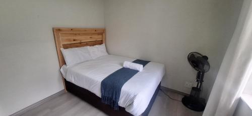 a small bedroom with a bed and a fan at Stylish 4-Bed Oasis - Pool Garden BackupPower in Johannesburg