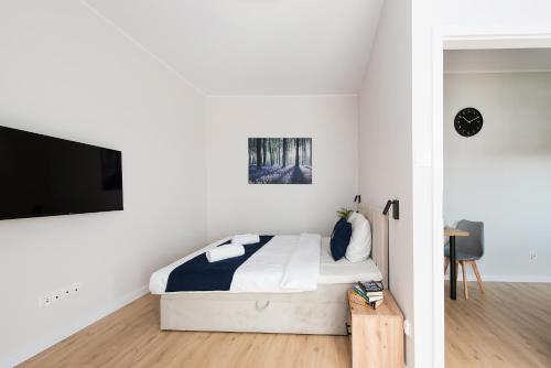 a white bedroom with a bed and a flat screen tv at Central Apartments by Bed&Bath in Kraków