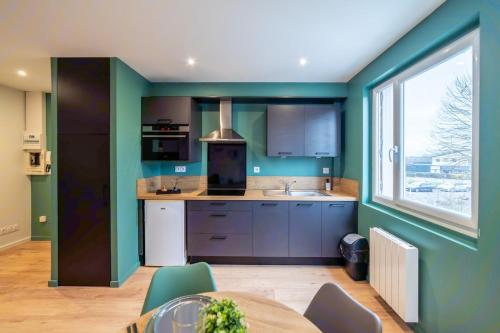 une cuisine avec des murs verts, une table et une fenêtre dans l'établissement Le Green Spot, gare, IUT, rocade WisdhomeConciergerie, à Rodez