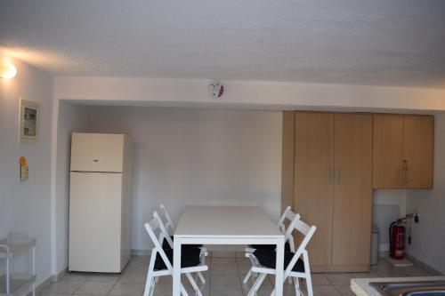 a kitchen with a white table and chairs and a refrigerator at Traditional apartment in nature in Kouvaláta
