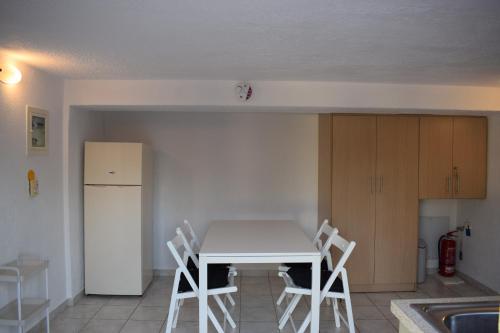 a kitchen with a white table and white chairs at Traditional apartment in nature in Kouvaláta