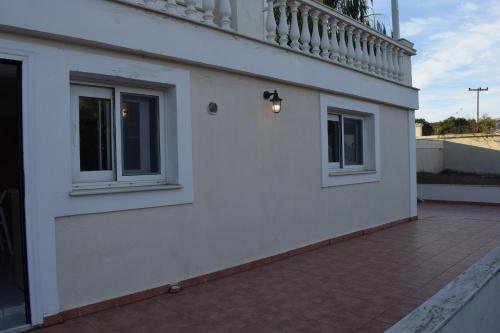 a white building with two windows and a balcony at Traditional apartment in nature in Kouvaláta