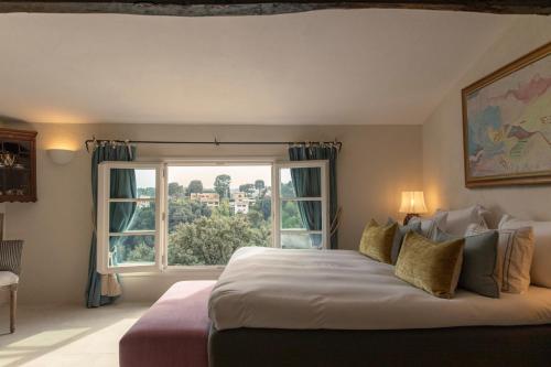 a bedroom with a large bed and a large window at Château Le Cagnard in Cagnes-sur-Mer