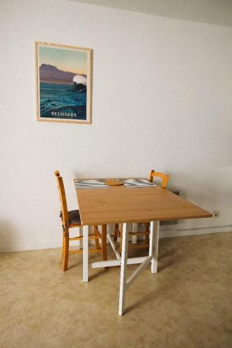 une table en bois avec deux chaises et une photo sur le mur dans l'établissement Studio Bidart Plage d'Erretegia, à Bidart