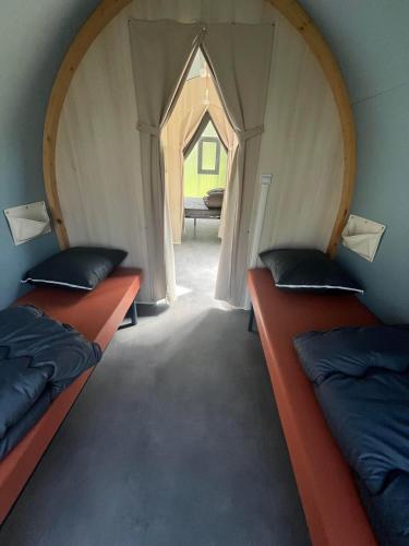 deux lits dans une petite pièce avec une porte cintrée dans l'établissement Camping le Convivial CocoSweet 4 personnes, à Saint-Martial-de-Nabirat