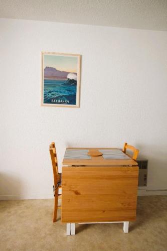 une table en bois dans une pièce avec un tableau sur le mur dans l'établissement Studio Bidart Plage d'Erretegia, à Bidart