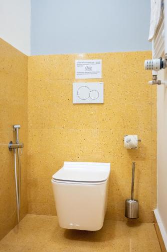 a white toilet in a bathroom with a yellow wall at Ciccio Rooms and breakfast - Self check-in in Palermo