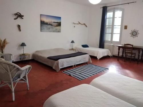 una stanza con due letti, un tavolo e delle sedie di Le Mas d'Icard a Saintes-Maries-de-la-Mer
