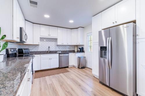 a kitchen with white cabinets and a stainless steel refrigerator at Clearwater Hideaway w Huge Lap POOL 7 min to BEACH in Clearwater