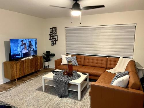 a living room with a couch and a flat screen tv at Clearwater Hideaway w Huge Lap POOL 7 min to BEACH in Clearwater