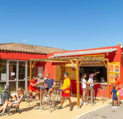 eine Gruppe von Personen, die vor einem Restaurant an einem Tisch sitzen in der Unterkunft Mobilhome 6 places Domaine de Chaussy in Lagorce