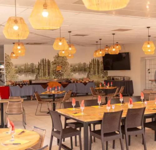 ein Esszimmer mit Tischen und Stühlen und Kronleuchtern in der Unterkunft Mobilhome 6 places Domaine de Chaussy in Lagorce