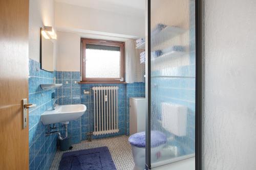 a blue tiled bathroom with a toilet and a sink at Ferienwohnung Karrach in Bernau im Schwarzwald