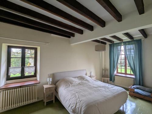 Un dormitorio con una cama blanca y dos ventanas. en La colline enchantée, en Saint-Martin-dʼOrdon