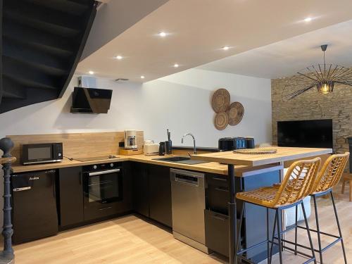 une cuisine avec des appareils noirs et un comptoir avec des tabourets dans l'établissement La Terrasse de l'Elorn vue exceptionnelle, à Le Relecq-Kerhuon