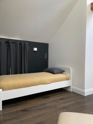a white bed with a black headboard in a room at Le Clos de la Pomponnette in Pomponne