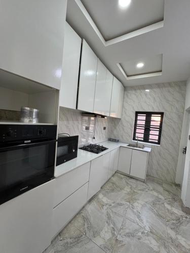 a kitchen with white cabinets and black appliances at 2bedroom luxury apartment in Lekki