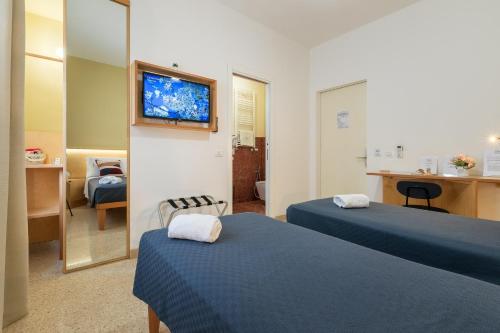 a room with two beds and a tv on a wall at Ciccio Rooms and breakfast - Self check-in in Palermo