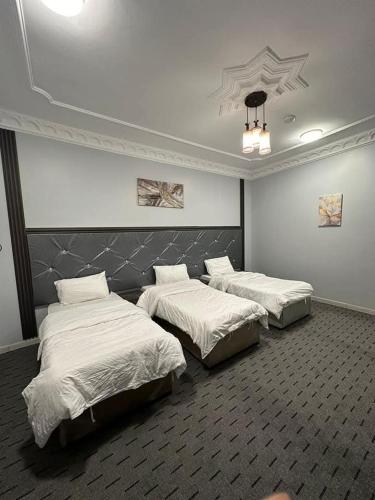 three beds in a room with white sheets at Al Ghazali Suites, اجنحة الغزالي للشقق المفروشه in Medina