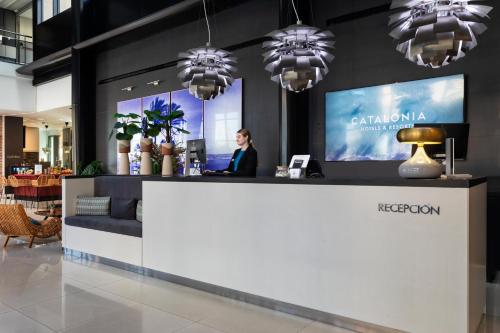a woman standing at a reception desk in a lobby at Catalonia Málaga in Málaga