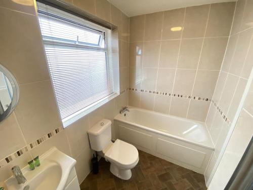 a white bathroom with a toilet and a sink at The Fern Two Bedroom Escape in South Norwood