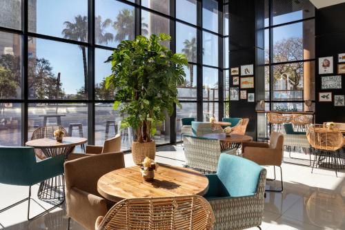 a restaurant with a wooden table and chairs and windows at Catalonia Málaga in Málaga