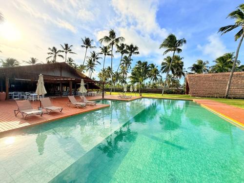 ein großer Swimmingpool mit Stühlen und Palmen in der Unterkunft Naca Boutique Hotel in Pôrto de Pedras