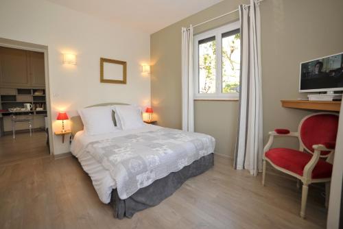 a bedroom with a bed and a window and a red chair at La Rosace in Chartres