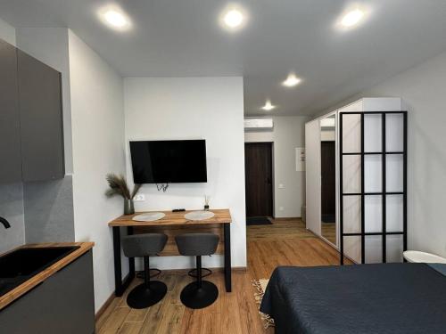 a bedroom with a desk with two chairs and a television at Smart House Apartments in Lviv