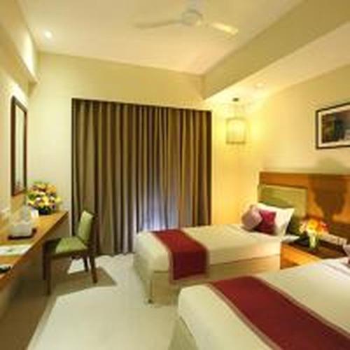 a hotel room with two beds and a desk at Jk Park Residency Perambra in Mennānyam