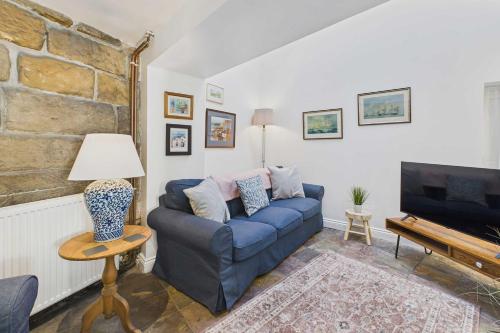a living room with a blue couch and a tv at Host & Stay - Luna Cottage in Staithes