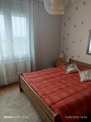 - une chambre avec un grand lit rouge et une fenêtre dans l'établissement Le lac, la neige,la vue, à La Tour-dʼAuvergne